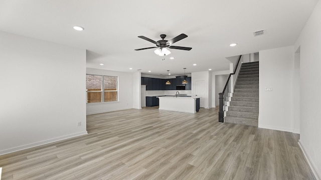 unfurnished living room with stairway, a ceiling fan, light wood finished floors, and recessed lighting