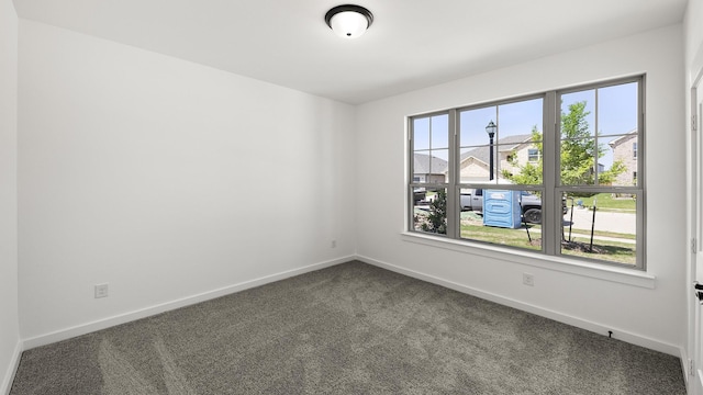 unfurnished room featuring dark carpet and baseboards