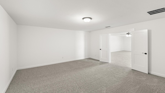 carpeted empty room with a ceiling fan, visible vents, and baseboards