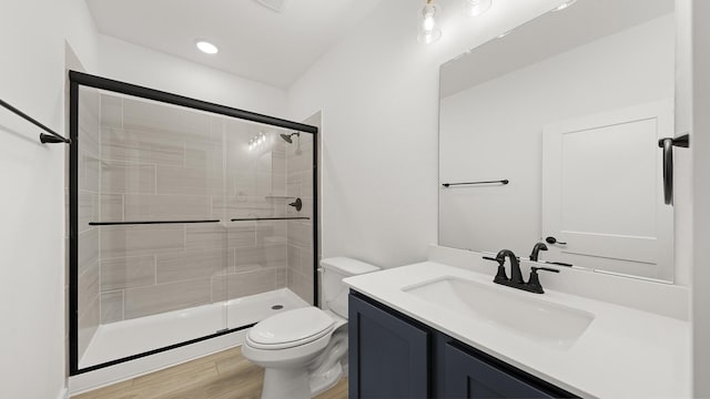 full bath with vanity, wood finished floors, toilet, and a stall shower