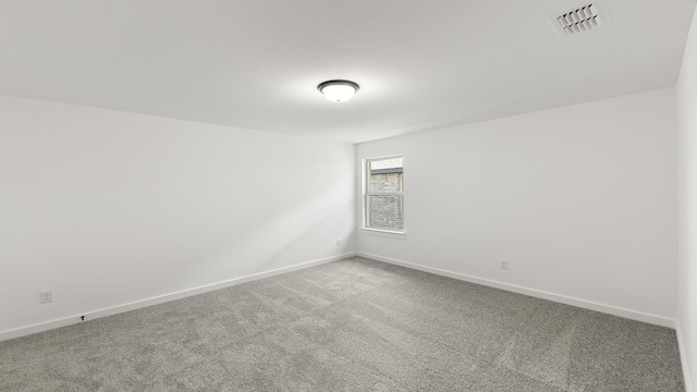 carpeted spare room featuring baseboards and visible vents
