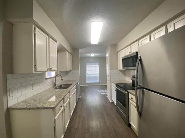 kitchen with white cabinets, sink, light stone counters, dark hardwood / wood-style flooring, and stainless steel appliances