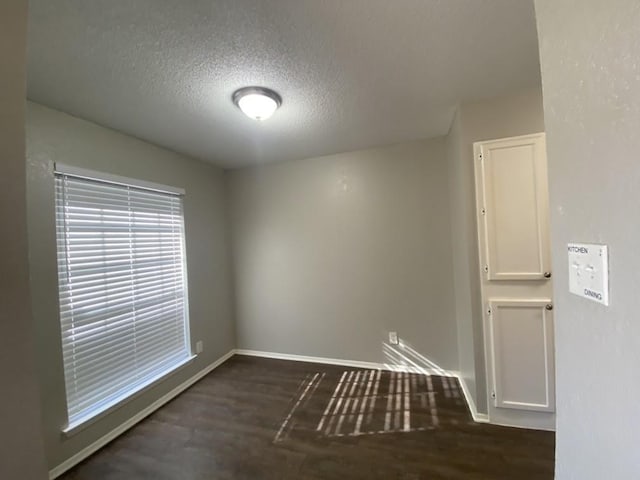 empty room with a textured ceiling and dark hardwood / wood-style floors