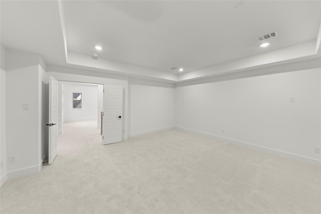 interior space with a tray ceiling and light colored carpet