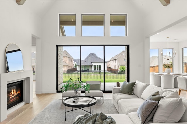 2671 Pelican Pt, Prosper, TX 75078 - living room with high vaulted ceiling, a chandelier, light wood-style flooring, a glass covered fireplace, and a residential view