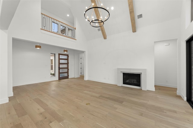 unfurnished living room featuring a notable chandelier, light hardwood / wood-style flooring, high vaulted ceiling, and beamed ceiling