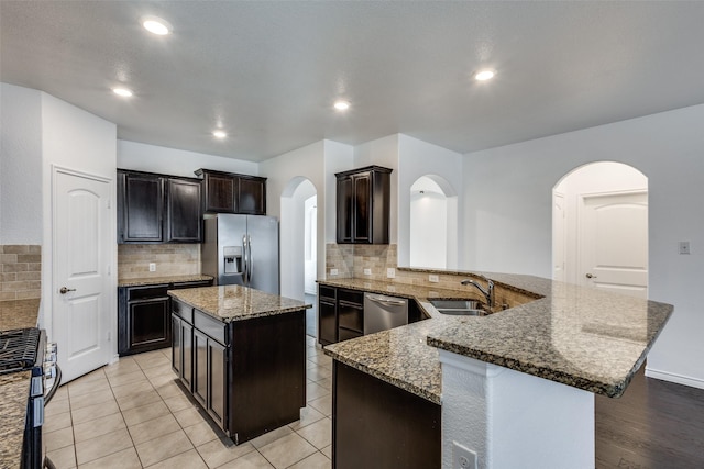 kitchen featuring dark stone countertops, sink, a center island, and appliances with stainless steel finishes