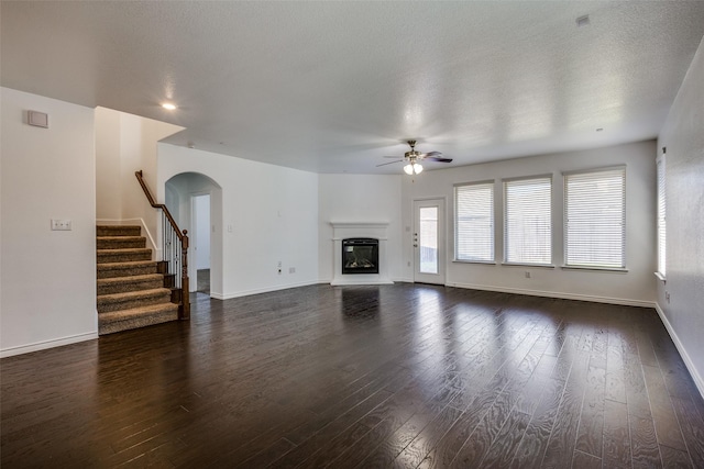 unfurnished living room featuring dark hardwood / wood-style floors, ceiling fan, and a textured ceiling