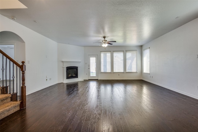 unfurnished living room featuring ceiling fan, dark wood-type flooring, and a textured ceiling