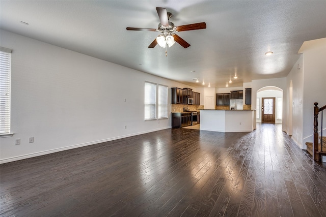 unfurnished living room featuring ceiling fan, dark wood-type flooring, and a textured ceiling