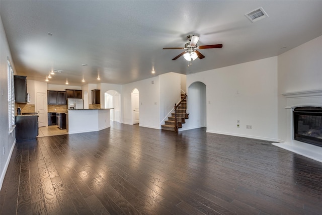 unfurnished living room with ceiling fan and dark wood-type flooring