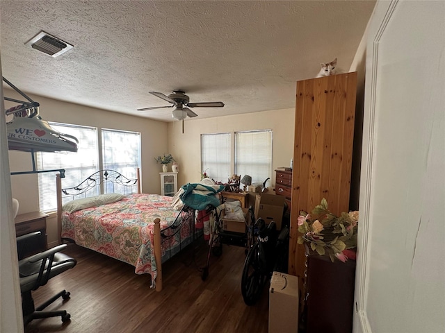 bedroom with a textured ceiling, ceiling fan, and dark wood-type flooring