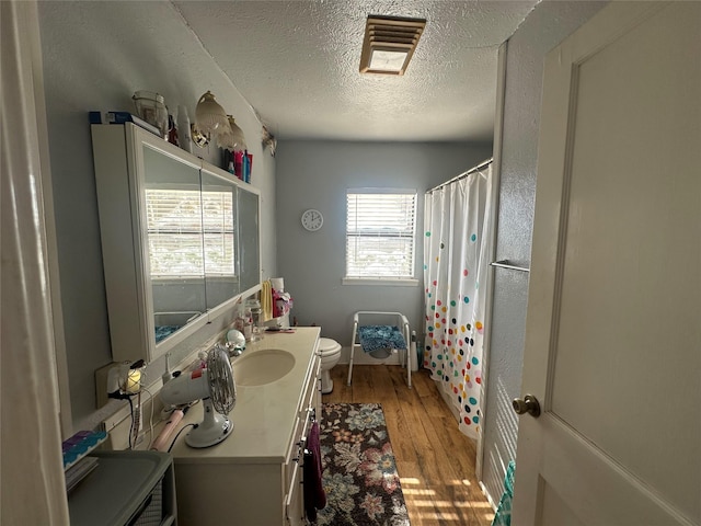 bathroom featuring a shower with curtain, vanity, a textured ceiling, hardwood / wood-style floors, and toilet