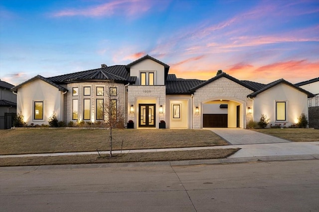 view of front facade with a lawn, french doors, and a garage