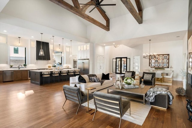 living room featuring beamed ceiling, wood-type flooring, ceiling fan with notable chandelier, and high vaulted ceiling