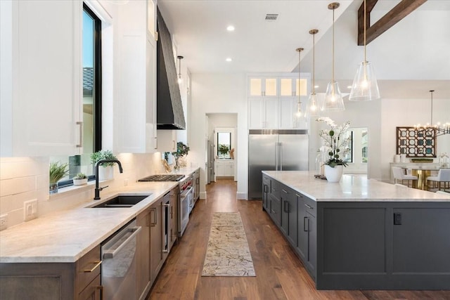 kitchen with high quality appliances, white cabinetry, plenty of natural light, and decorative light fixtures