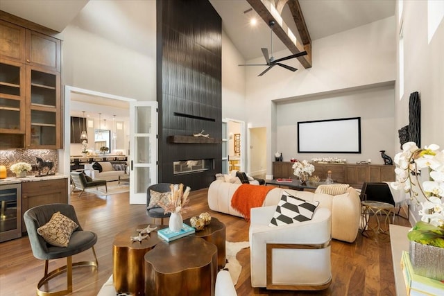 living room with hardwood / wood-style flooring, ceiling fan, beamed ceiling, and high vaulted ceiling