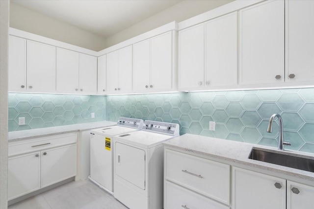 laundry area featuring cabinets, separate washer and dryer, and sink