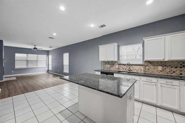 kitchen featuring dark stone countertops, sink, a center island, and white cabinets