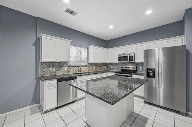 kitchen with stainless steel appliances, a kitchen island, sink, and white cabinets