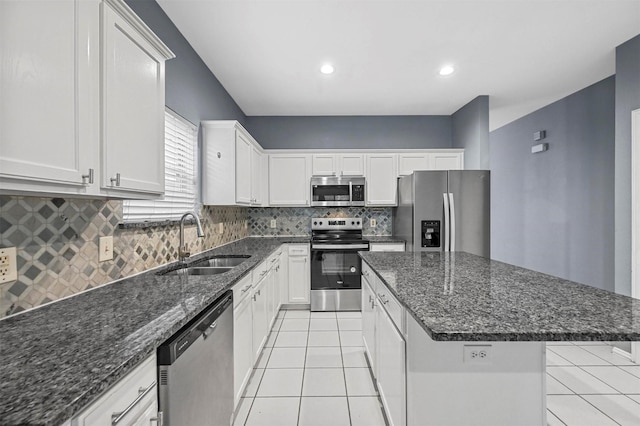 kitchen with light tile patterned flooring, a kitchen island, white cabinetry, sink, and stainless steel appliances