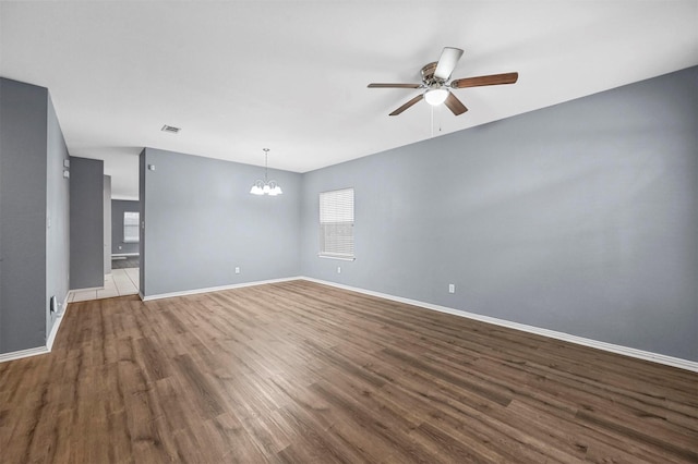 spare room with hardwood / wood-style flooring and ceiling fan with notable chandelier