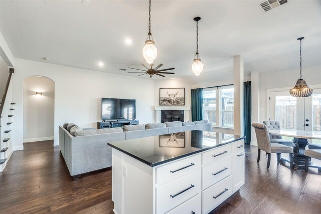 kitchen with pendant lighting, white cabinetry, dark wood-type flooring, and a tiled fireplace