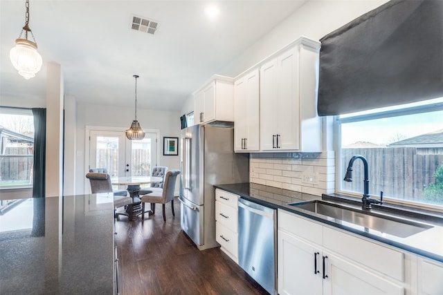 kitchen with dark hardwood / wood-style flooring, stainless steel appliances, sink, pendant lighting, and white cabinets