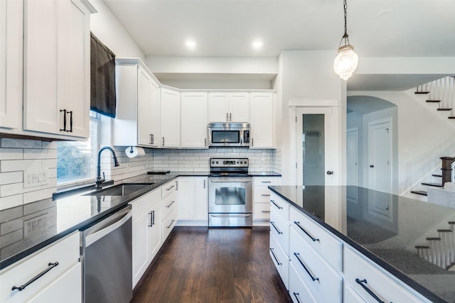 kitchen with appliances with stainless steel finishes, white cabinetry, dark wood-type flooring, and sink