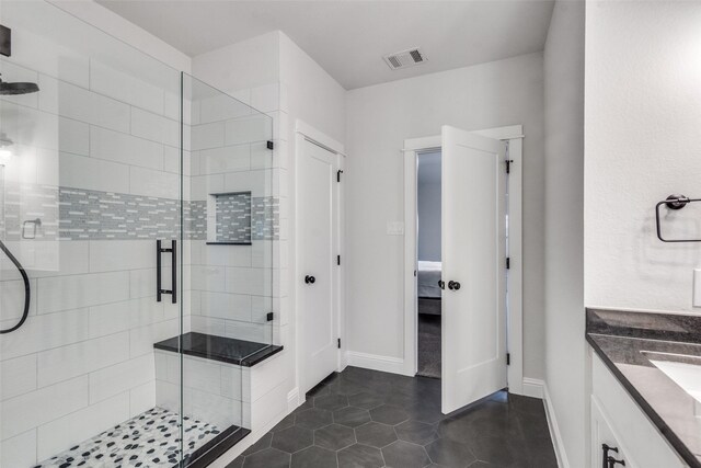 bathroom with tile patterned flooring, vanity, and walk in shower