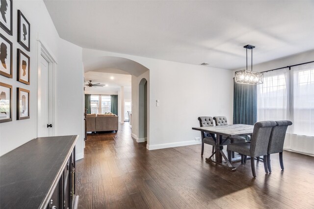 dining room with ceiling fan with notable chandelier and dark wood-type flooring