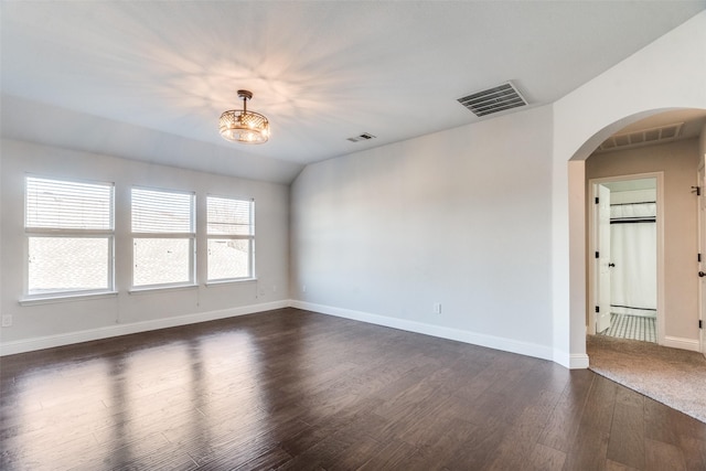 spare room featuring lofted ceiling and dark wood-type flooring