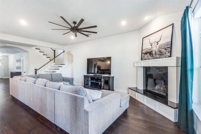 living room with a tile fireplace, dark hardwood / wood-style flooring, and ceiling fan