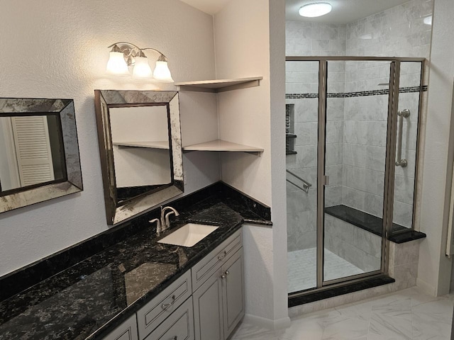 bathroom featuring marble finish floor, a shower stall, and vanity