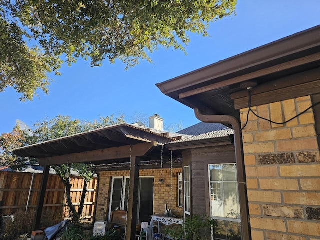 back of house featuring brick siding and fence