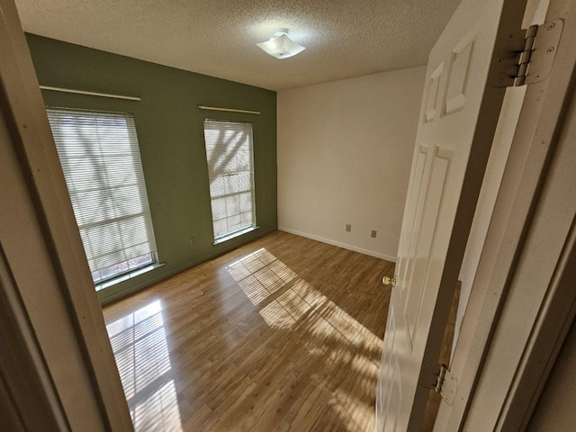 empty room with wood-type flooring, a textured ceiling, and a wealth of natural light