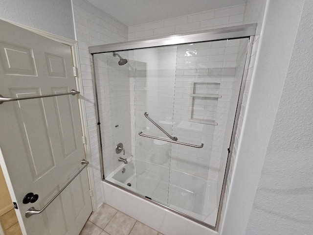 bathroom with shower / bath combination with glass door and tile patterned flooring