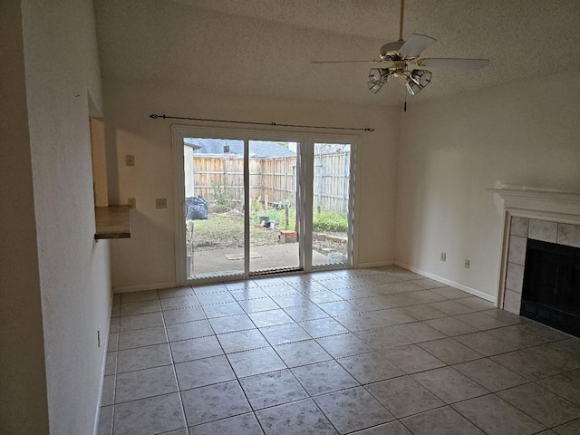 unfurnished living room with a tiled fireplace, ceiling fan, light tile patterned floors, and a textured ceiling