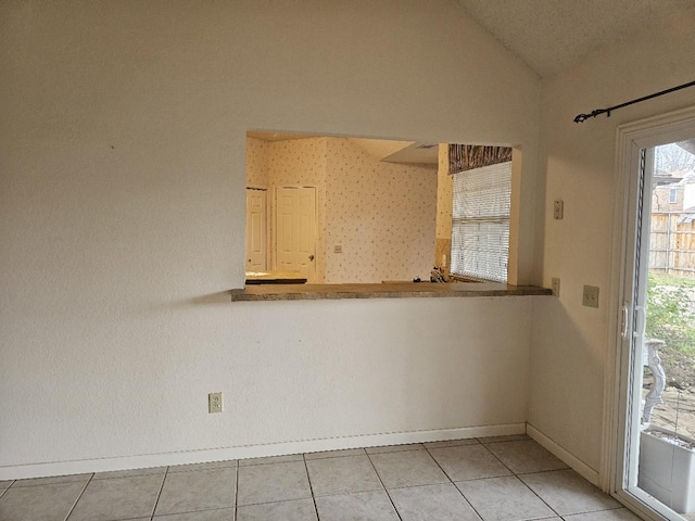 unfurnished room with lofted ceiling and light tile patterned floors