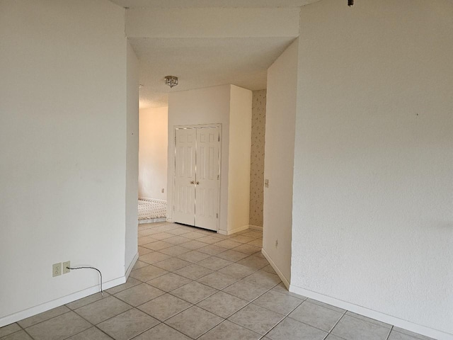 spare room featuring light tile patterned floors and baseboards