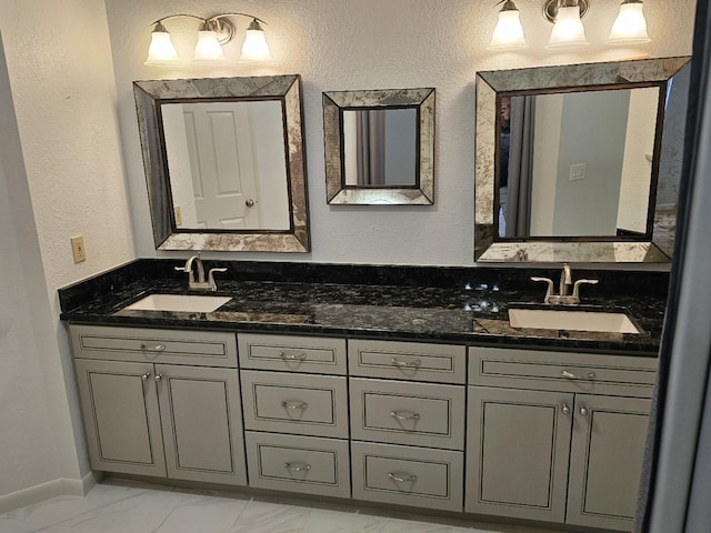 bathroom with double vanity, marble finish floor, a sink, and a textured wall