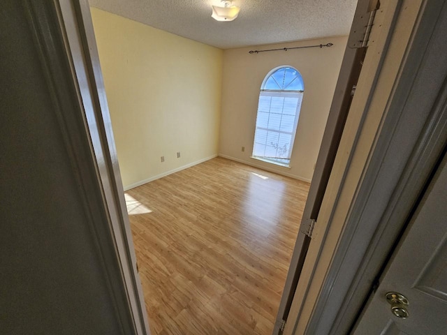 spare room featuring a textured ceiling and light hardwood / wood-style floors