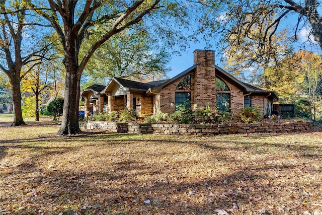 exterior space with brick siding, a chimney, and a front lawn