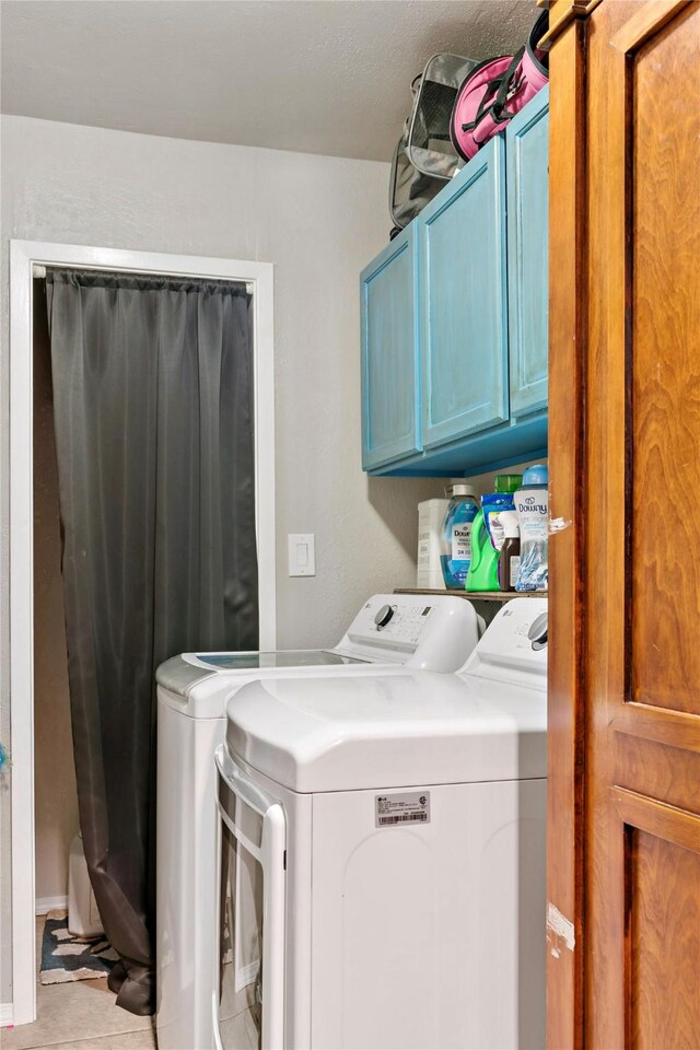 laundry area featuring cabinet space, light tile patterned floors, and washing machine and clothes dryer