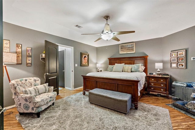 bedroom featuring a ceiling fan, wood finished floors, visible vents, and baseboards