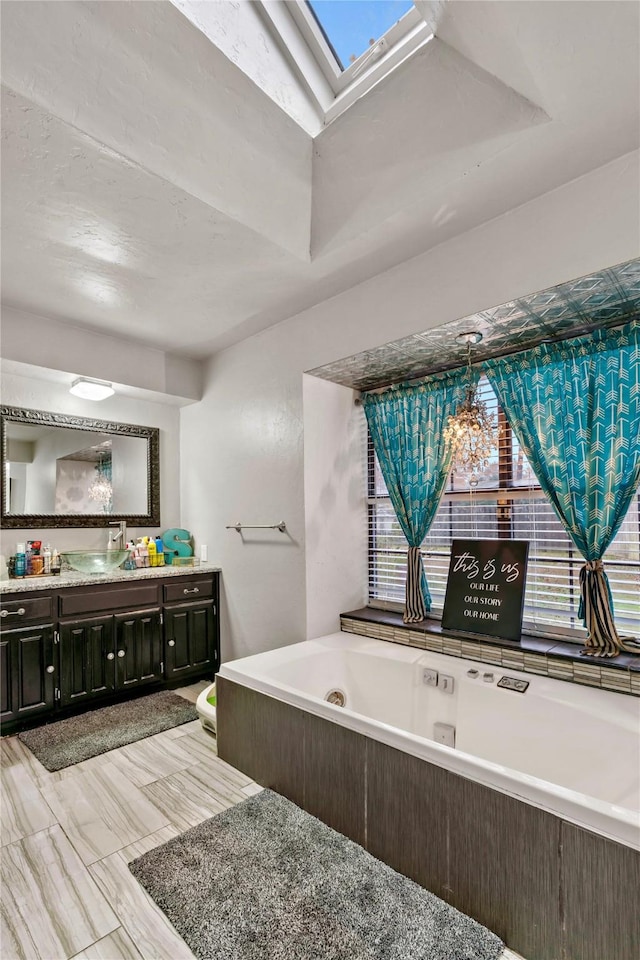 full bath featuring a skylight, a garden tub, a wealth of natural light, and vanity