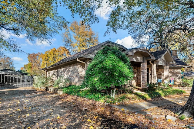 view of property exterior with stone siding, brick siding, and fence