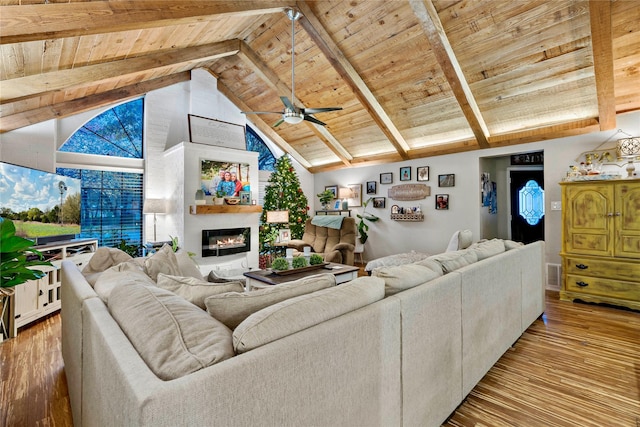 living room with a glass covered fireplace, wood ceiling, and light wood-style floors