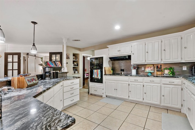 3075 Clark Ln, Paris, TX 75460 - kitchen with under cabinet range hood, white cabinetry, backsplash, and hanging light fixtures