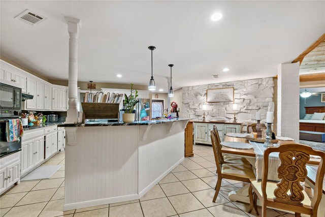 kitchen featuring visible vents, white cabinetry, hanging light fixtures, a center island, and ornate columns